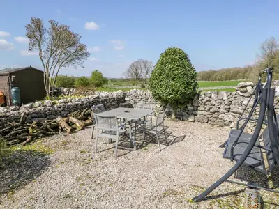 a table and chairs in front of a stone wall at Rosemary Cottage in Carnforth