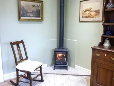 a room with a chair and a wood stove at The Old Forge in Waddington