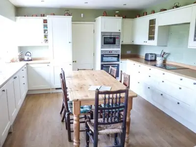 a kitchen with a wooden table and white cabinets at The Old Forge in Waddington