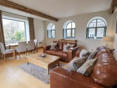 a living room with a leather couch and a table at Hazel Cottage in Ulverston