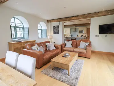 a living room with brown leather furniture and a table at Hazel Cottage in Ulverston