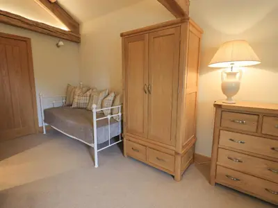 a bedroom with a cabinet and a chair and a lamp at Hazel Cottage in Ulverston