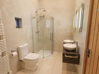 a bathroom with a shower and a toilet and a sink at Keepers Cottage in Ulverston