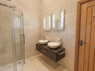 a bathroom with two sinks and a glass shower at Keepers Cottage in Ulverston