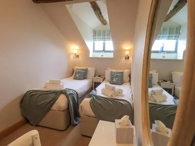 a attic room with two beds and a mirror at Keepers Cottage in Ulverston