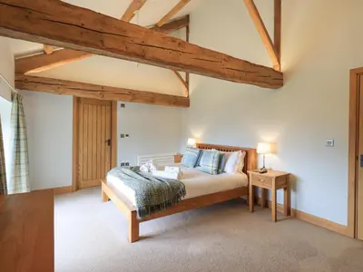 a bedroom with a bed and wooden beams at Keepers Cottage in Ulverston