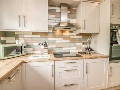 a kitchen with white cabinets and a microwave at Primrose Cottage in Ulverston
