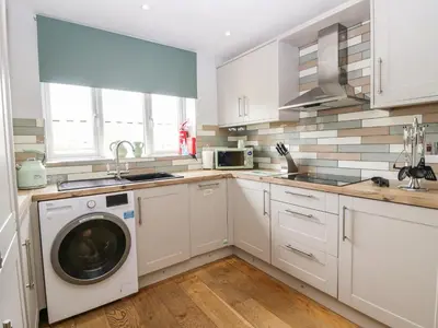 a kitchen with white cabinets and a washing machine at Primrose Cottage in Ulverston