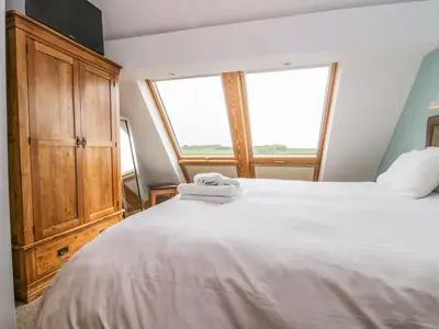 a bedroom with a large white bed and a window at Primrose Cottage in Ulverston