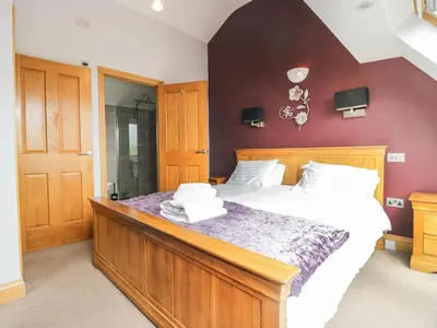 a bedroom with a large bed with white sheets at Primrose Cottage in Ulverston