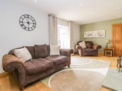 a living room with a couch and a clock on the wall at Primrose Cottage in Ulverston