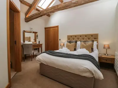 a bedroom with a large bed and a desk at Rowan Cottage in Ulverston