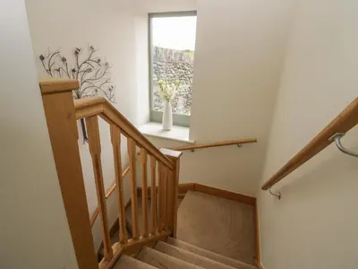 a staircase with a window and a vase with flowers at Rowan Cottage in Ulverston