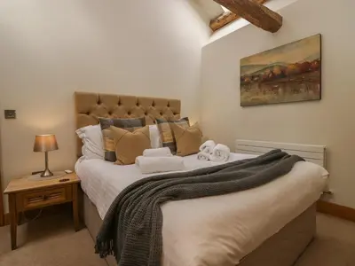 a bedroom with a large bed and a painting on the wall at Rowan Cottage in Ulverston