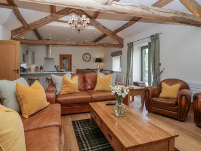 a living room with leather furniture and a table at Rowan Cottage in Ulverston