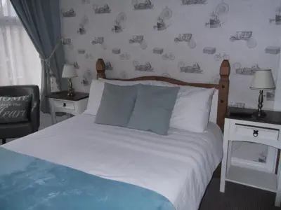 a bedroom with a bed and two tables and a chair at J's Mayfair Guest House in Blackpool