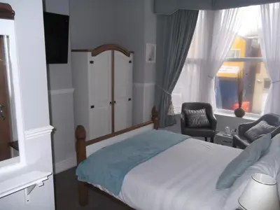 a bedroom with a bed and a chair and a window at J's Mayfair Guest House in Blackpool