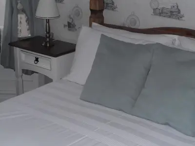 a bed with white sheets and a night stand with a lamp at J's Mayfair Guest House in Blackpool