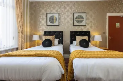 two beds in a hotel room with white sheets at Adelaide Lodge - Town Centre - Opposite Winter Gardens in Blackpool