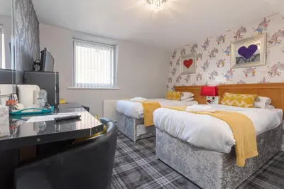 a hotel room with two beds and a desk at Adelaide Lodge - Town Centre - Opposite Winter Gardens in Blackpool
