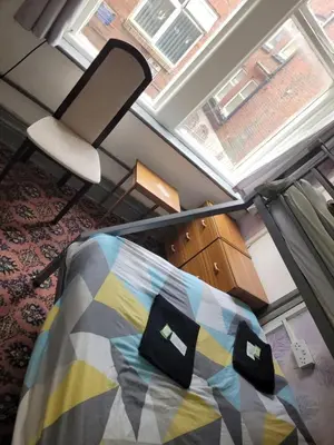 a bedroom with a bed and a chair and a window at The Merlin Hotel in Blackpool