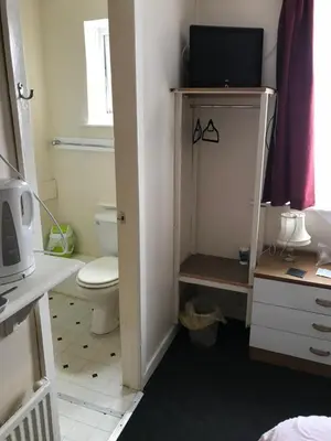 a bathroom with a toilet and a tv on a shelf at The Merlin Hotel in Blackpool