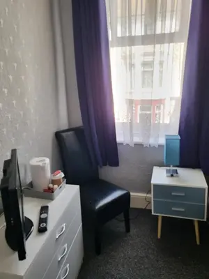 a room with a chair and a dresser and a window at Talbot House in Blackpool
