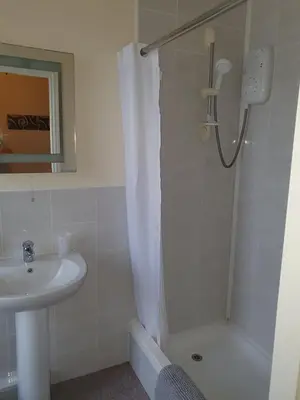 a white bathroom with a shower and a sink at Hawthorn House in Blackpool