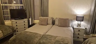 a hotel room with two beds and a television at Hawthorn House in Blackpool