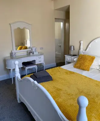 a bedroom with a bed with a dresser and a mirror at Hawthorn House in Blackpool