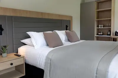 a bedroom with a large white bed with a wooden headboard at Mytton Fold Hotel, Ribble Valley in Langho