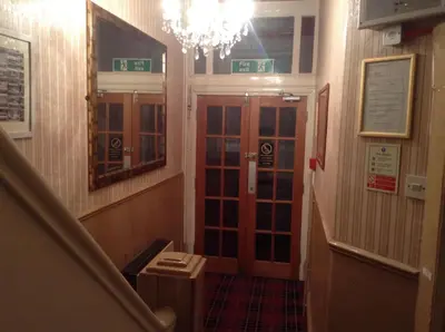 a hallway with a staircase with a door and a chandelier at Victoria Hotel Blackpool in Blackpool