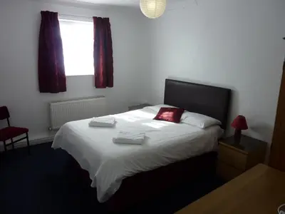 a bedroom with a white bed with red pillows and a window at The Mercury in Bolton