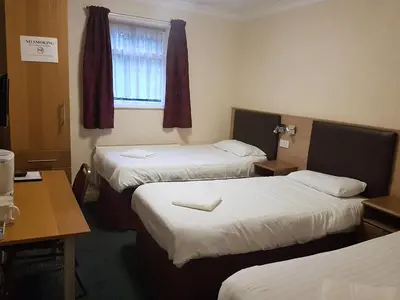 a room with three beds and a table and a window at The Mercury in Bolton