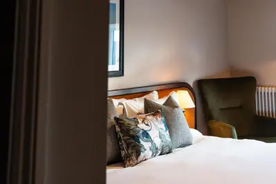 a bedroom with a bed with pillows and a chair at Longlands Inn & Cottages in Carnforth
