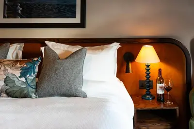 a bed with white sheets and pillows next to a lamp at Longlands Inn & Cottages in Carnforth