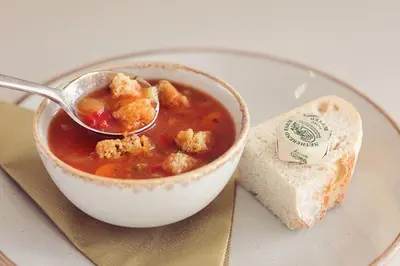 a bowl of soup with a spoon and a piece of bread at Longlands Inn & Cottages in Carnforth