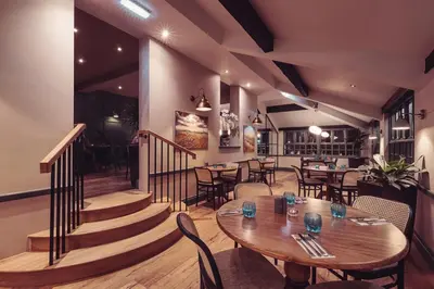 a restaurant with tables and chairs and a staircase at Longlands Inn & Cottages in Carnforth