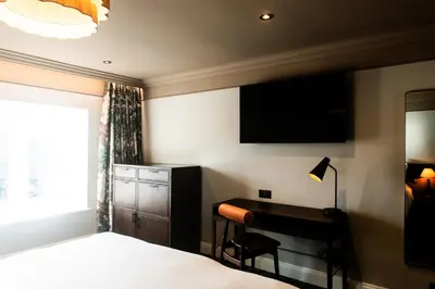 a bedroom with a bed and a desk and a television at Longlands Inn & Cottages in Carnforth