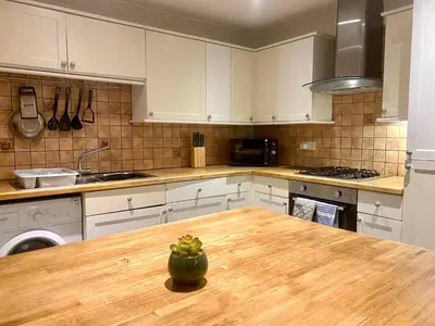 a kitchen with white cabinets and a wooden table at Fabrik Apartments - Harrowside by Blackpool Service Apartements in Blackpool
