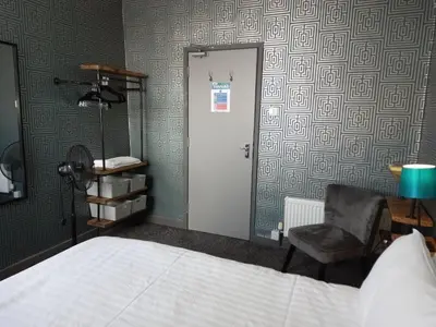 a bedroom with a bed and a chair and a door at Vinnie's Family Hotel in Blackpool