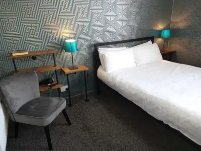 a hotel room with a bed and a chair at Vinnie's Family Hotel in Blackpool