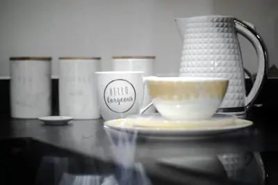 a glass table with a cup and a coffee mug at Liverpool Harrow Road Sleeps 6- Infinity Apartment in Liverpool