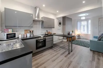 a kitchen with a counter top and a living room at Liverpool Harrow Road Sleeps 6- Infinity Apartment in Liverpool