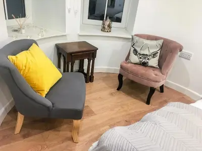 a living room with two chairs and a table at Garden Apartment in Grange Over Sands