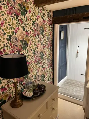 a lamp on a dresser in a room with floral wallpaper at Low Fell in Ulverston