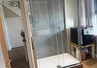 a glass shower in a room with a television at Chateau julie in Liverpool