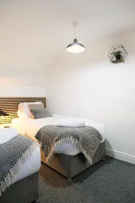a bedroom with two beds with white walls at The Docklands Apartment by Serviced Living Liverpool in Liverpool