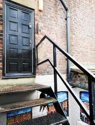 a staircase with a black door and a brick building at The Docklands SA by Serviced Living Liverpool in Liverpool