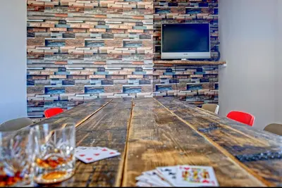 a wooden table with chairs and a tv on a brick wall at The Docklands SA by Serviced Living Liverpool in Liverpool